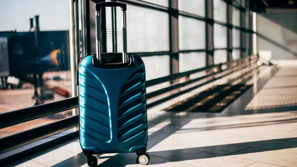 Close-up shot of a blue suitcase at an airport.