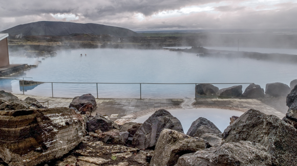 Two people in Myvatn nature baths with clouds overhead.