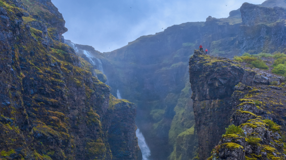 Hikers at a viewpoint of Glymur Waterfall in Iceland.