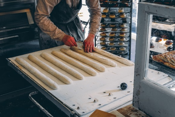 Man rolling bread dough in a bakery in Reykjavík.