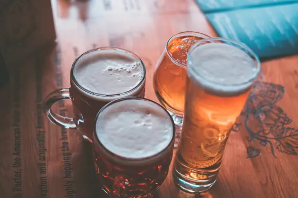 Beers in different types of glasses on a wooden table.