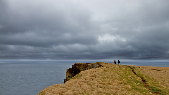 Hikers on a cliff edge, overlooking the sea