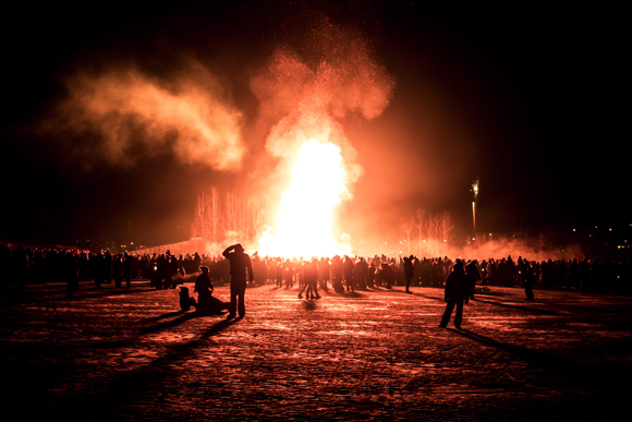 People gathered around a towering bonfire during New Year’s celebration in Iceland.