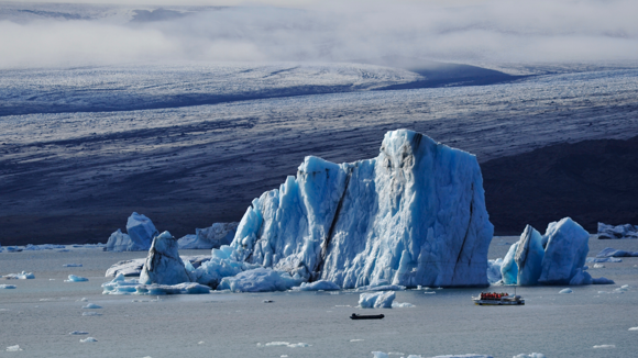  two boats approaching an epic iceberg floating in Jökulsárlón Glacier Lagoon