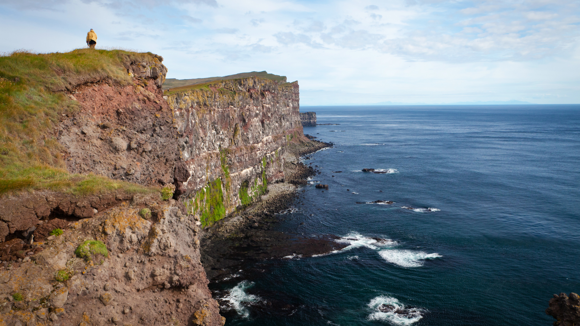  Látrabjarg cliffside with a person walking along the grassy tops.