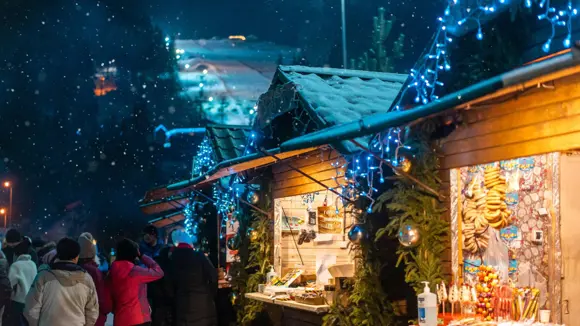 People visiting Christmas markets with snow falling.