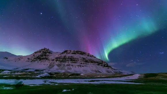 Snow-covered Kirkjufell in winter under the Northern Lights.