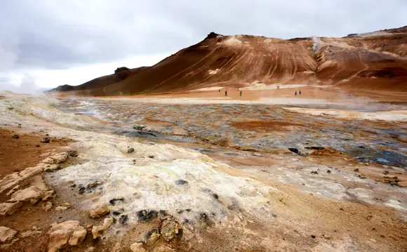 People standing and photographing a steaming crater in Námaskarð Pass.